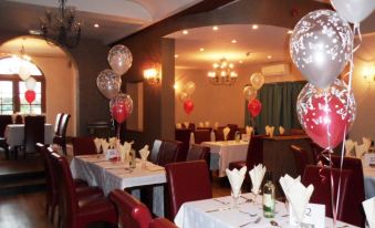 a dining room with tables set for a party , decorated with balloons and red chairs at Skylark Hotel
