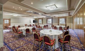 a large , empty conference room with round tables and chairs set up for a meeting or event at Reigate Manor Hotel