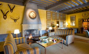 a cozy living room with two couches , a fireplace , and a clock on the wall at Parador de Jarandilla
