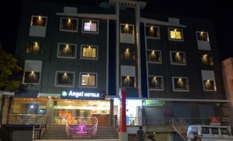 "a modern building with a lit sign and large windows advertising "" angel hotels "" at night" at Angel Hotels