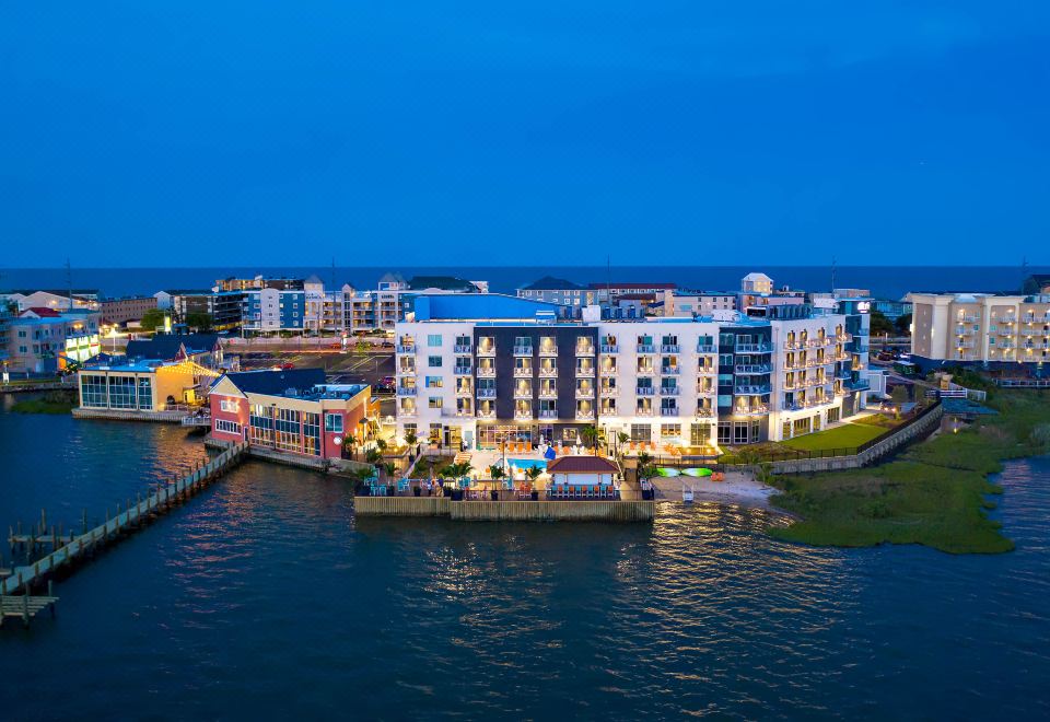 a large building with a hotel and restaurant on its side is situated near a body of water at Aloft Ocean City