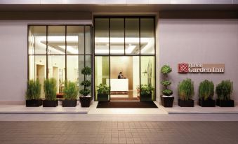 a modern building entrance with large glass doors and windows , along with potted plants on the floor at Hilton Garden Inn Puchong