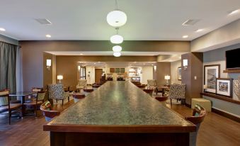 a large dining table surrounded by chairs in a room , with a view of the kitchen at Hampton Inn-DeKalb (Near the University)