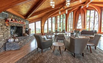 a spacious living room with wooden ceiling , stone walls , and large windows overlooking a forested area at General Butler State Resort Park