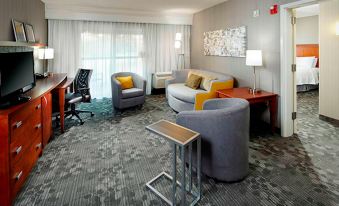 a hotel room with a couch , chairs , and tables , creating a comfortable living space at Courtyard Akron Stow