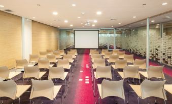 a large conference room with rows of chairs arranged in a semicircle , and a projector screen mounted on the wall at Radisson Hotel Santa Cruz