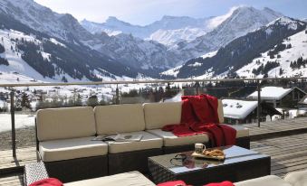 a living room with a couch , coffee table , and red blanket overlooking snowy mountains and a valley at The Cambrian