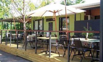 an outdoor dining area with a wooden deck and several tables and chairs , as well as a canopy over them at Hidden Valley Holiday Park