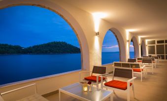 a room with a view of the ocean has orange cushions and white tables at Aminess Lume Hotel