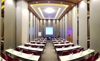 a large conference room with rows of tables and chairs , a projector screen , and a podium at Grand Singgie Hotel