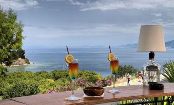 two glasses of drinks with lemon slices on the table , overlooking a body of water at Hotel Carina