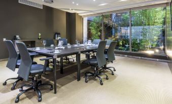 a conference room with a long table , several chairs , and a large window overlooking greenery at Bog Hotel