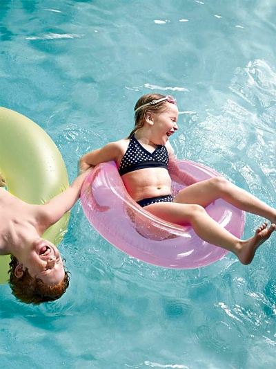 a young girl is floating on a pink inner tube while a man slides down the edge of the pool at Country Inn & Suites by Radisson, Watertown, SD