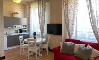 a living room with a red couch , white dining table , and chairs , as well as a kitchen area with a refrigerator and sink at Sunrise Beach Villa