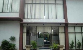 a large glass building with a red roof and white walls , featuring two potted plants in front at Jazz Hotel Palu