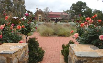 a beautiful garden with a brick pathway , flowers , and a building in the background , under a cloudy sky at Copper House