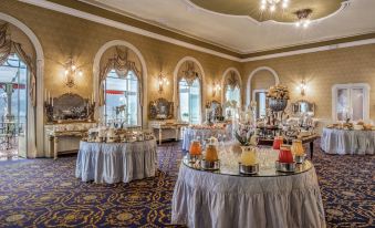 a large dining room filled with tables and chairs , where people are enjoying a buffet - style meal at Grand Hotel Tremezzo