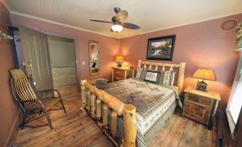 a cozy bedroom with a wooden bed , a ceiling fan , and a painting on the wall at RoosterComb Inn