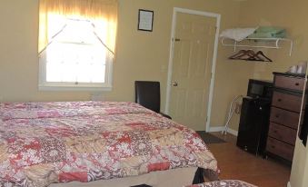 a cozy bedroom with a bed , window , and door , decorated with floral bedding and framed picture at The Clipper Inn