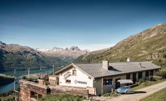 a white building with a blue roof is situated on a hillside overlooking mountains and a lake at Badrutt's Palace Hotel St Moritz