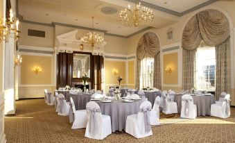 a well - decorated banquet hall with multiple tables covered in white tablecloths and chairs arranged for a formal event at Francis Marion Hotel