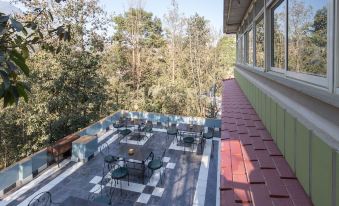 a rooftop patio area with multiple tables and chairs arranged for outdoor dining , surrounded by trees at Green Leaf Resort