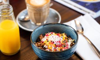 a bowl of food with toppings and a cup of coffee on a wooden table at Rydges Wellington Airport, an EVT hotel