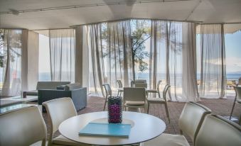 a dining room with a round table and chairs , as well as a couch in the background at Vitality Hotel Punta