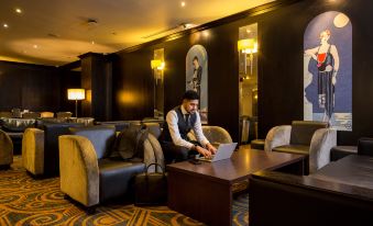 a man is sitting at a table in a dimly lit room , working on a laptop at President Hotel