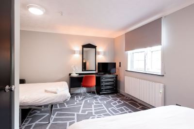 a modern hotel room with a bed , desk , and tv , along with white walls and gray carpet at Village Hotel Liverpool