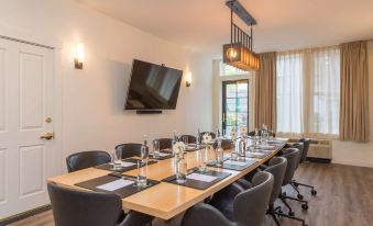 a conference room with a long wooden table , multiple chairs , and a large screen on the wall at The Brunswick Hotel