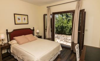 a bedroom with a bed , nightstand , and chair next to an open doorway leading to a garden at Villa Turistica de Bubion