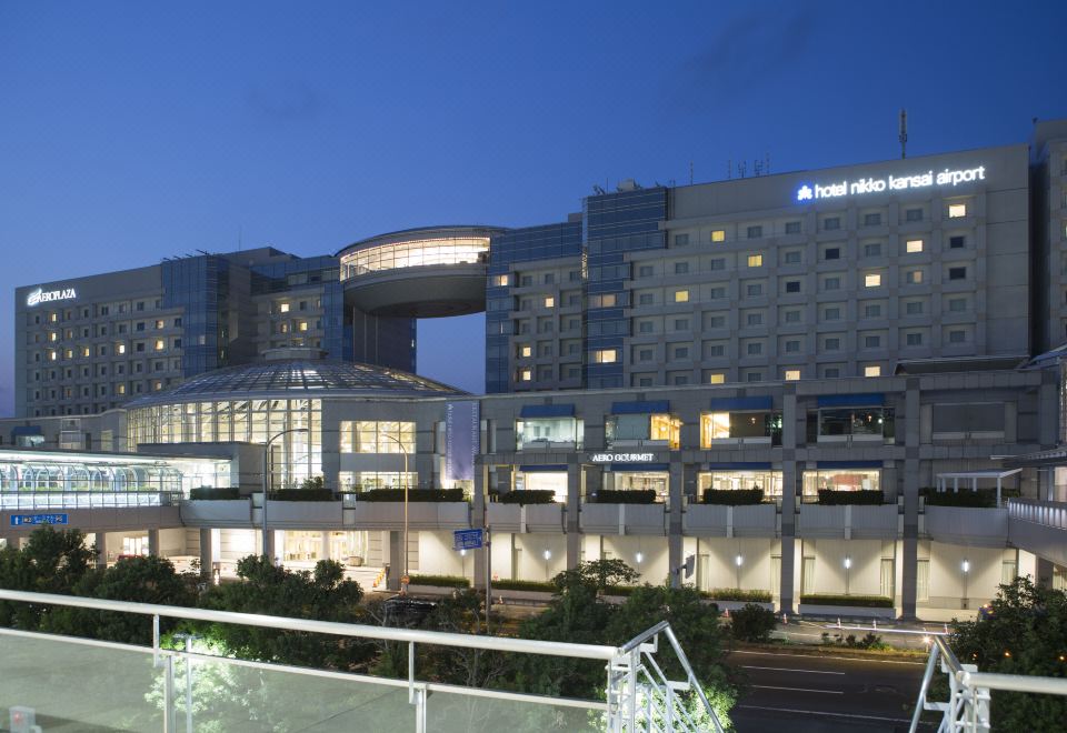 a large hotel building with a curved facade and several windows is lit up at night at Hotel Nikko Kansai Airport