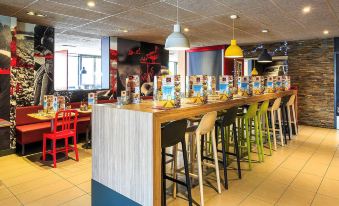 a dining area with a long wooden table surrounded by chairs , and a variety of food items on the table at Ibis Lyon Villefranche-Sur-Saône
