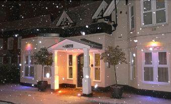 "a snowy night scene with a building that has been lit up and has the sign "" the postmark "" above it" at Manor Hotel