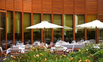 an outdoor dining area with umbrellas and tables set up in front of a building at Steigenberger Airport Hotel Amsterdam