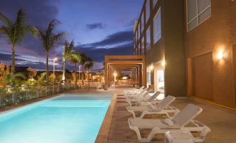 a large outdoor pool surrounded by lounge chairs , with palm trees in the background at Four Points by Sheraton Puntacana Village