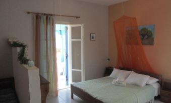 a bedroom with a large bed , orange mosquito net , and a door leading to an outdoor area at Anastasia