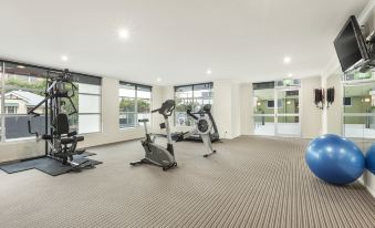 a well - equipped exercise room with various fitness equipment , including treadmills , stationary bikes , and a treadmill at Quest Breakfast Creek