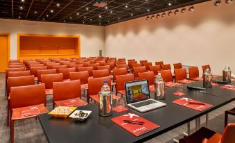 a conference room with rows of chairs arranged in a semicircle around a table , and a laptop on one of the tables at Glam Milano