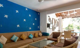 a living room with a blue wall featuring white stars , a brown couch , and two chairs at Casablanca