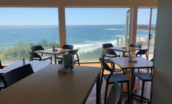 a dining area with tables and chairs is shown with a view of the ocean at Pacific Hotel Yamba