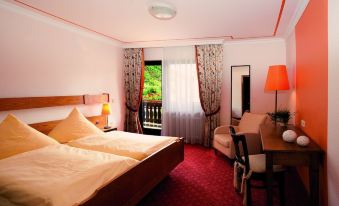 a hotel room with a large bed , red carpet , and an open door leading to a balcony at Moselhotel & Restaurant Zur Traube Gmbh