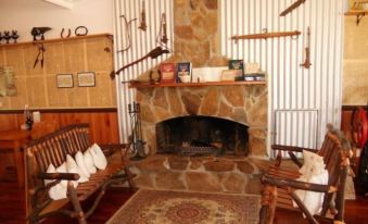 a cozy living room with a stone fireplace , wooden chairs , and various items hanging on the wall at Mountain View Country Inn