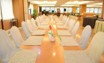 a long dining table set for a large group of people , with chairs arranged around it at Bay Hotel Srinakarin