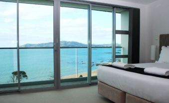 a bedroom with a large window overlooking the ocean and a bed in front of it at Doubtless Bay Villas