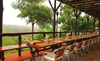 a wooden dining table with chairs set up on a covered patio overlooking a scenic view at Phu Pha Nam Resort
