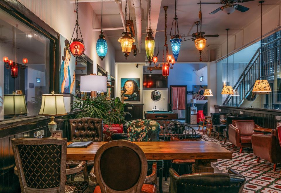 The room is illuminated by overhead lights and contains tables, chairs, and other furniture in the center at Poshpacker Flipflop Youth Hostel (Taikoo Li Chunxi Road Metro Station)