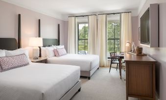 a hotel room with two beds , a desk , and a window , all decorated in white and grey colors at The Williams Inn