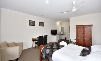 a hotel room with a king - sized bed , a dining table , and a tv . also a kitchen visible in the room at Inglewood Motel and Caravan Park Victoria